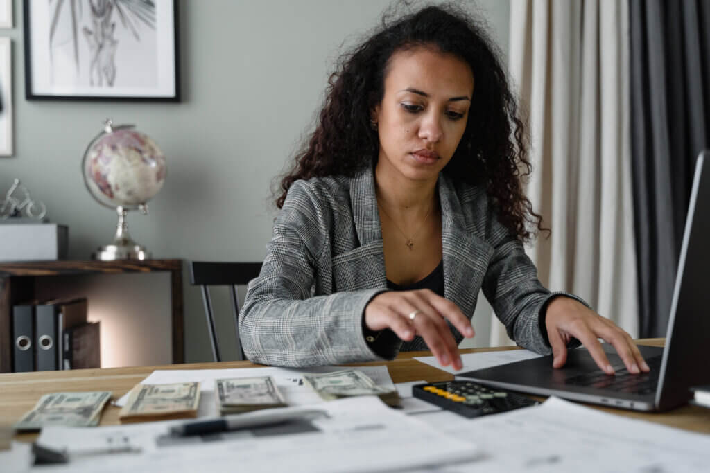 A woman in plaid blazer using her laptop and mobile phone