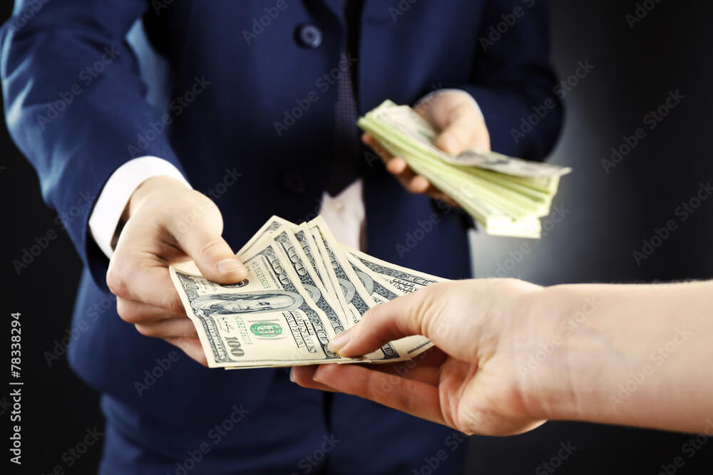 Businessman giving money on dark background