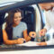 A young woman buys a car in a car showroom.