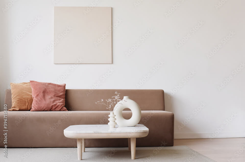 Blank picture frame mockup on white wall. White living room design. View of modern scandinavian style interior with sofa. Home staging and minimalism concept